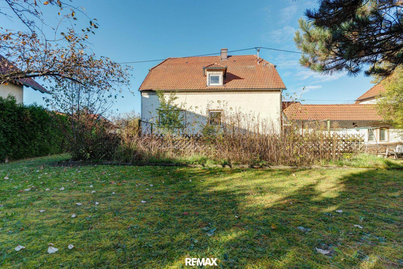 Rückseite des Hauses mit großem Garten, Rasenfläche und Blick auf die Umgebung.