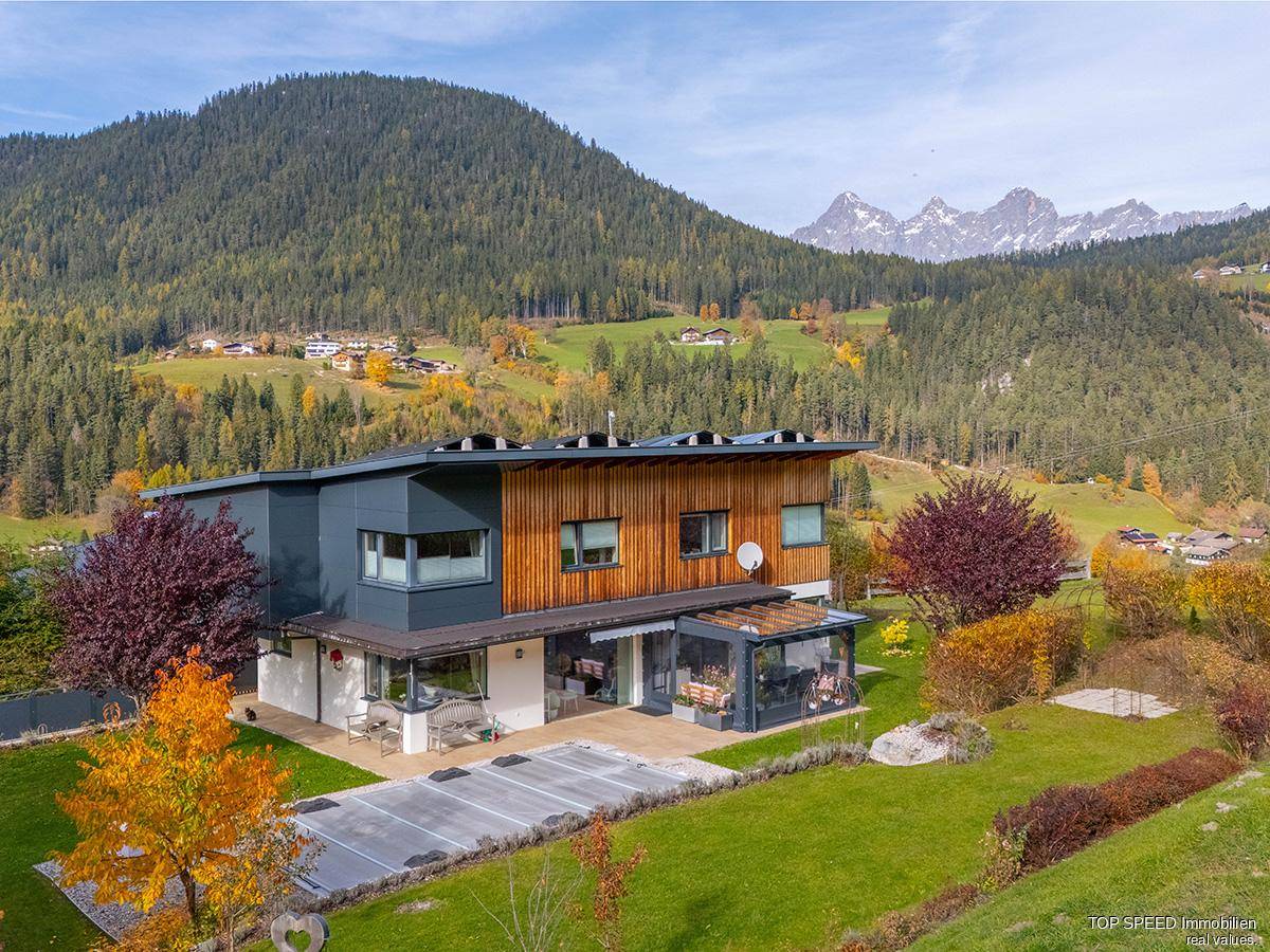 Modernes Haus mit großem Garten, überdachtem Pool und Bergblick im Herbst.
