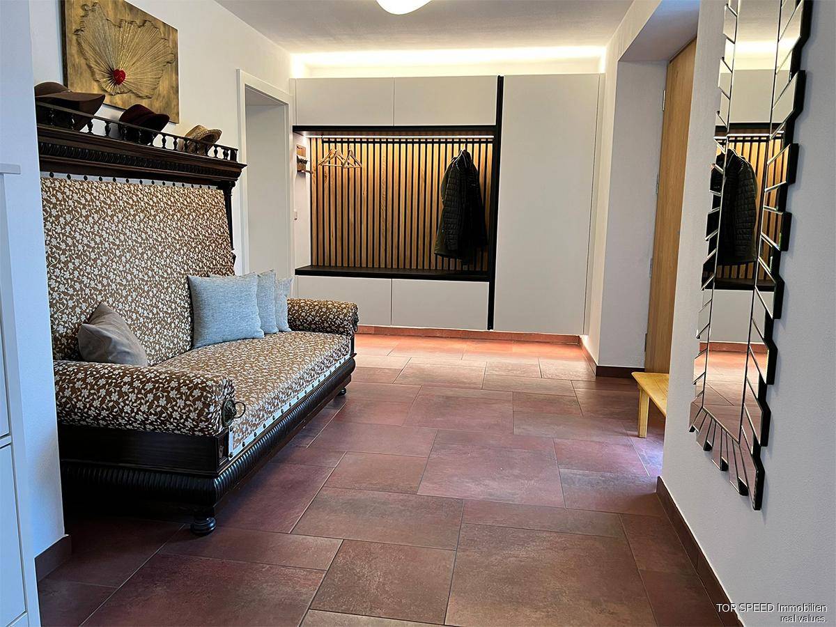 Geräumiger Eingangsbereich mit Sitzbank, integrierter Garderobe und Fliesenboden.