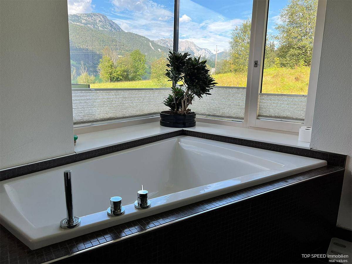 Badezimmer mit großer Badewanne und Panoramafenster, das einen beeindruckenden Bergblick bietet.