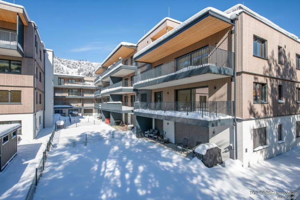 Moderne Wohngebäude im Winter mit schneebedeckten Dächern und Balkonen.
