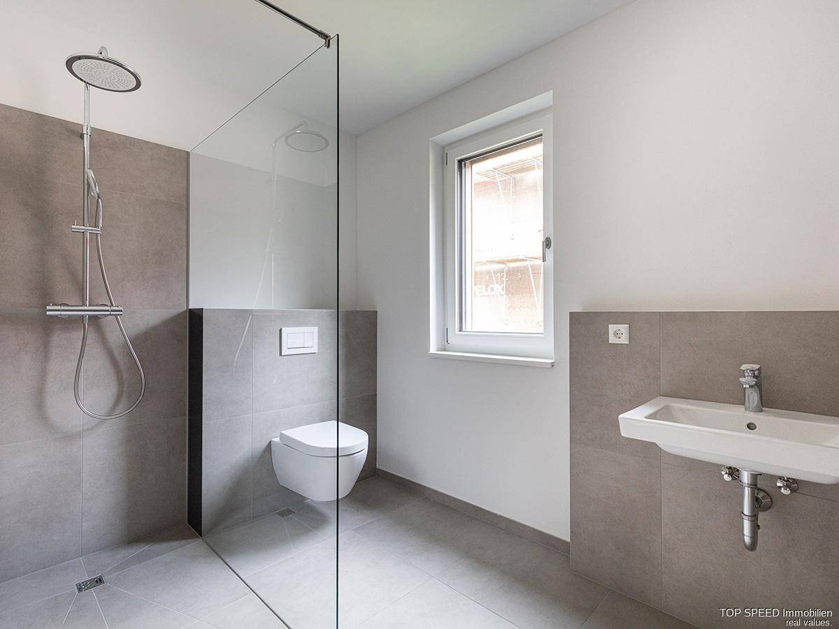 Modernes Badezimmer mit ebenerdiger Dusche, Wand-WC und Fenster für Tageslicht.