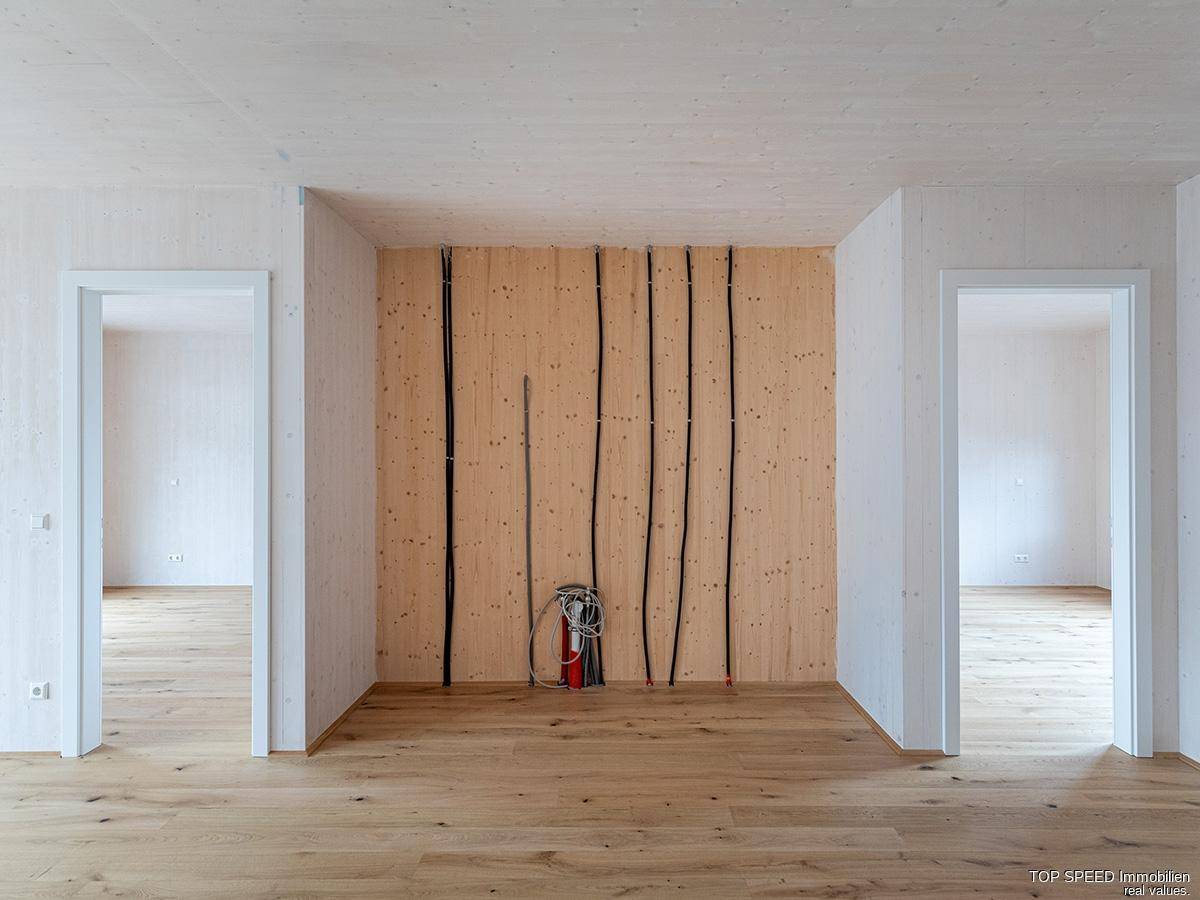 Detailansicht einer Holzwand mit vorbereiteten Elektroinstallationen und zwei Türöffnungen.