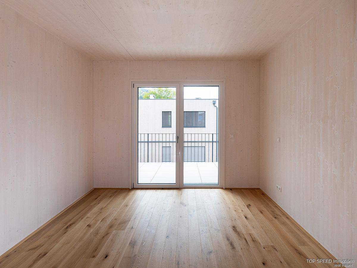 Helles Schlafzimmer mit Holzboden und direktem Zugang zu einem Balkon.