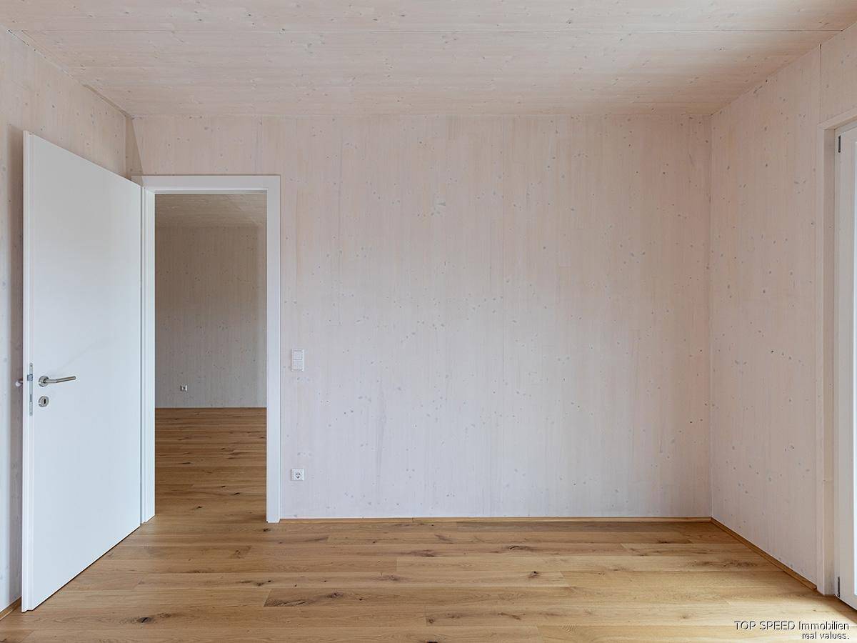 Unmöbliertes Schlafzimmer mit Holzboden und einer weißen Tür, bereit zur Gestaltung.