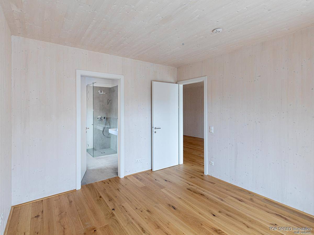 Schlafzimmer mit Holzboden und direktem Zugang zu einem modernen Badezimmer.