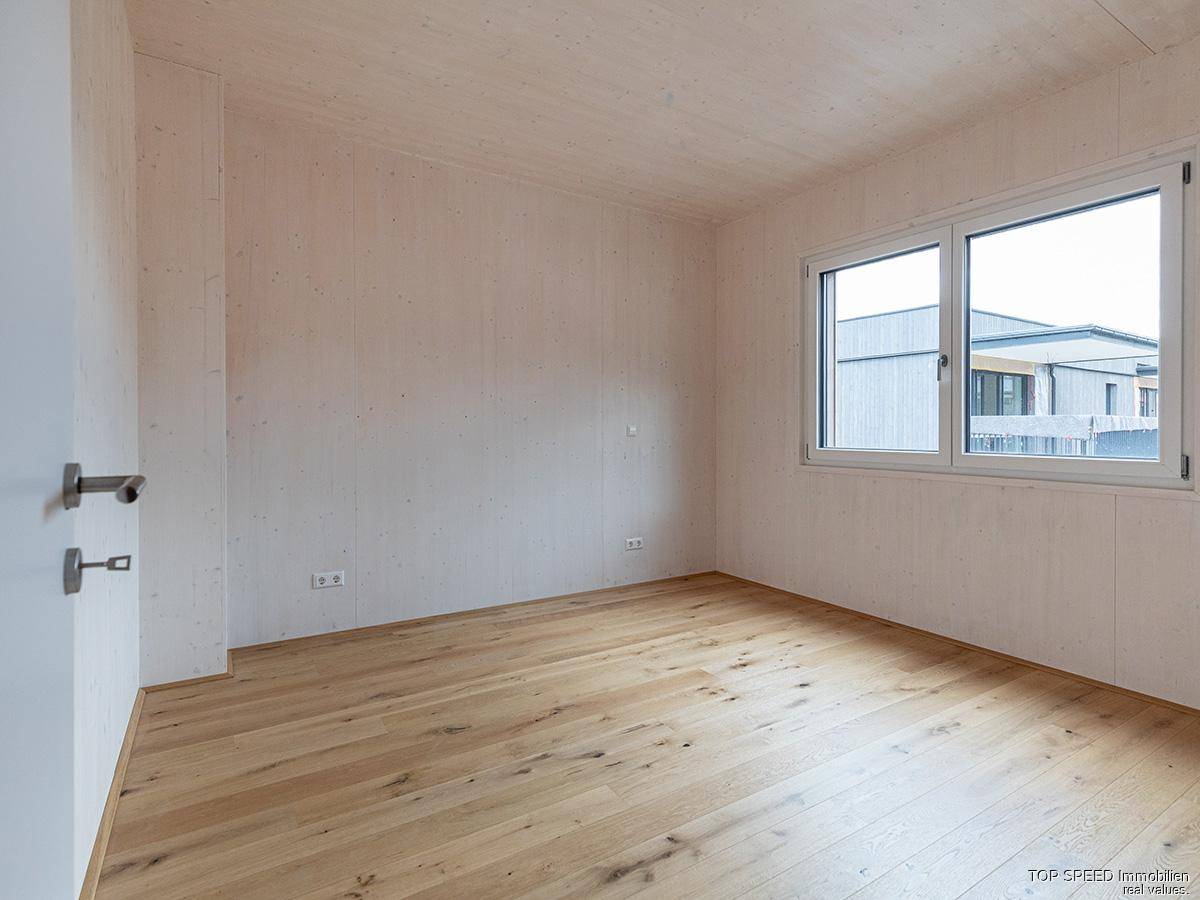 Helles, unmöbliertes Schlafzimmer mit Holzboden und Holzwänden, bereit zum Einrichten.