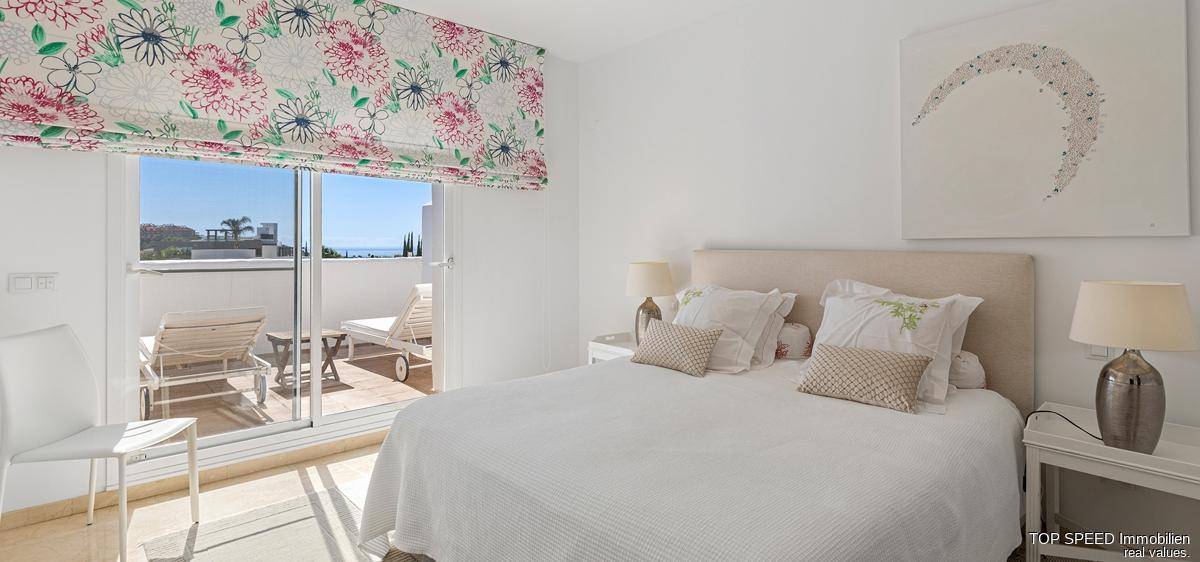 Helles Schlafzimmer mit Doppelbett und direktem Zugang zu einer sonnigen Terrasse.