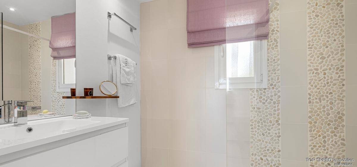 Modernes Badezimmer mit begehbarer Dusche und Fenster, ausgestattet mit hellen Kieselstein-Fliesen.