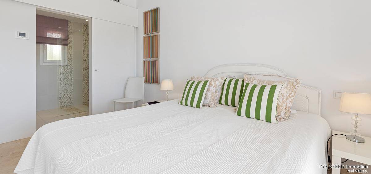 Ruhiges Schlafzimmer mit Doppelbett und direktem Zugang zu einem modernen Duschbad.