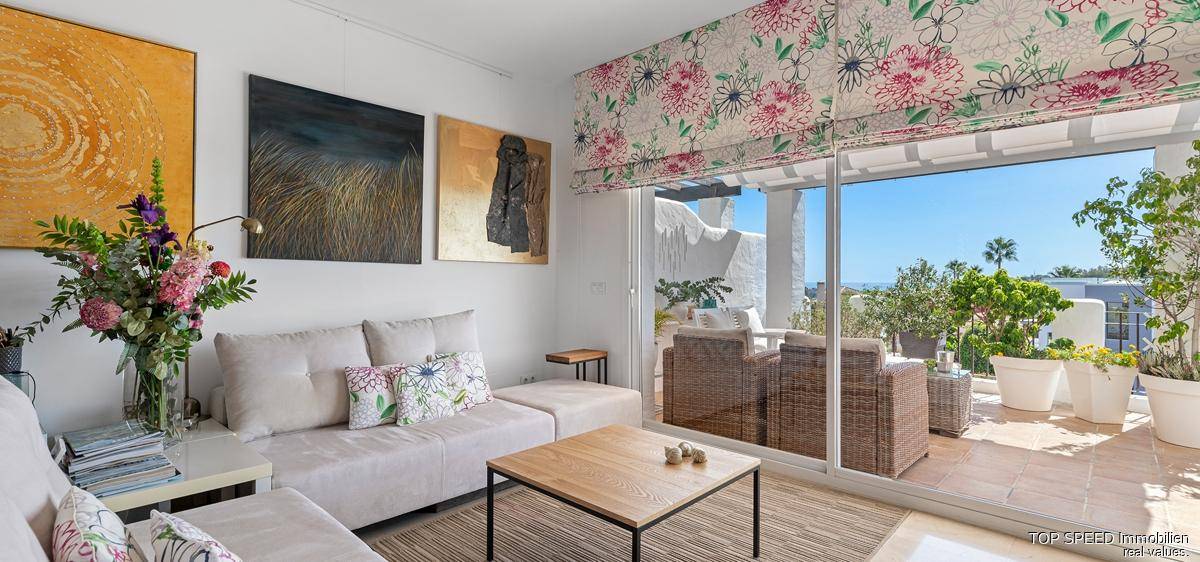 Lichtdurchflutetes Wohnzimmer mit großen Fenstern und Zugang zur Terrasse, modern eingerichtet.