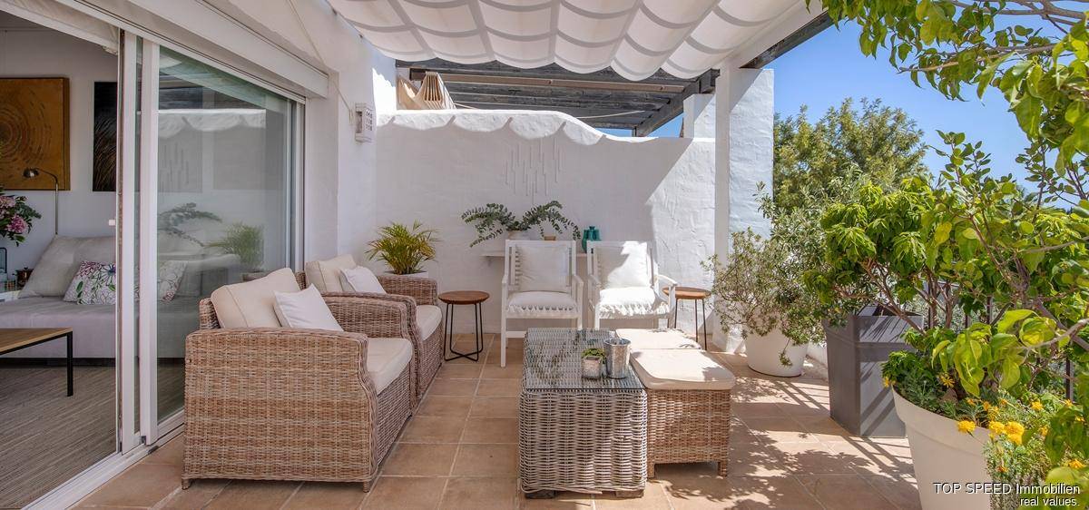 Geräumige Terrasse mit bequemen Loungemöbeln und Pflanzen, perfekt zum Entspannen im Freien.