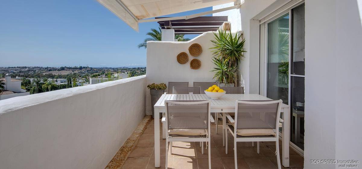 Sonniger Balkon mit Esstisch und Stühlen, ideal für Mahlzeiten im Freien mit Weitblick.