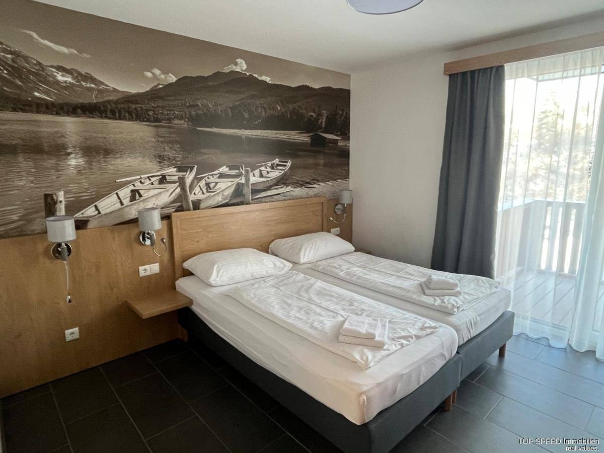 Schlafzimmer mit zwei Einzelbetten, Wandtapete mit Bergmotiv und Zugang zum Balkon.