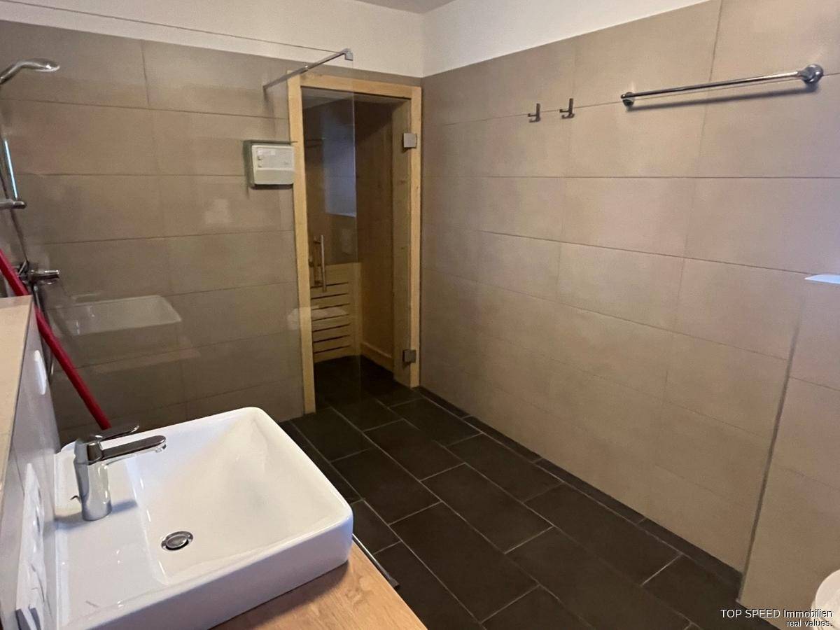 Modernes Badezimmer mit Dusche, Einzelwaschbecken und integrierter Sauna für Entspannung.