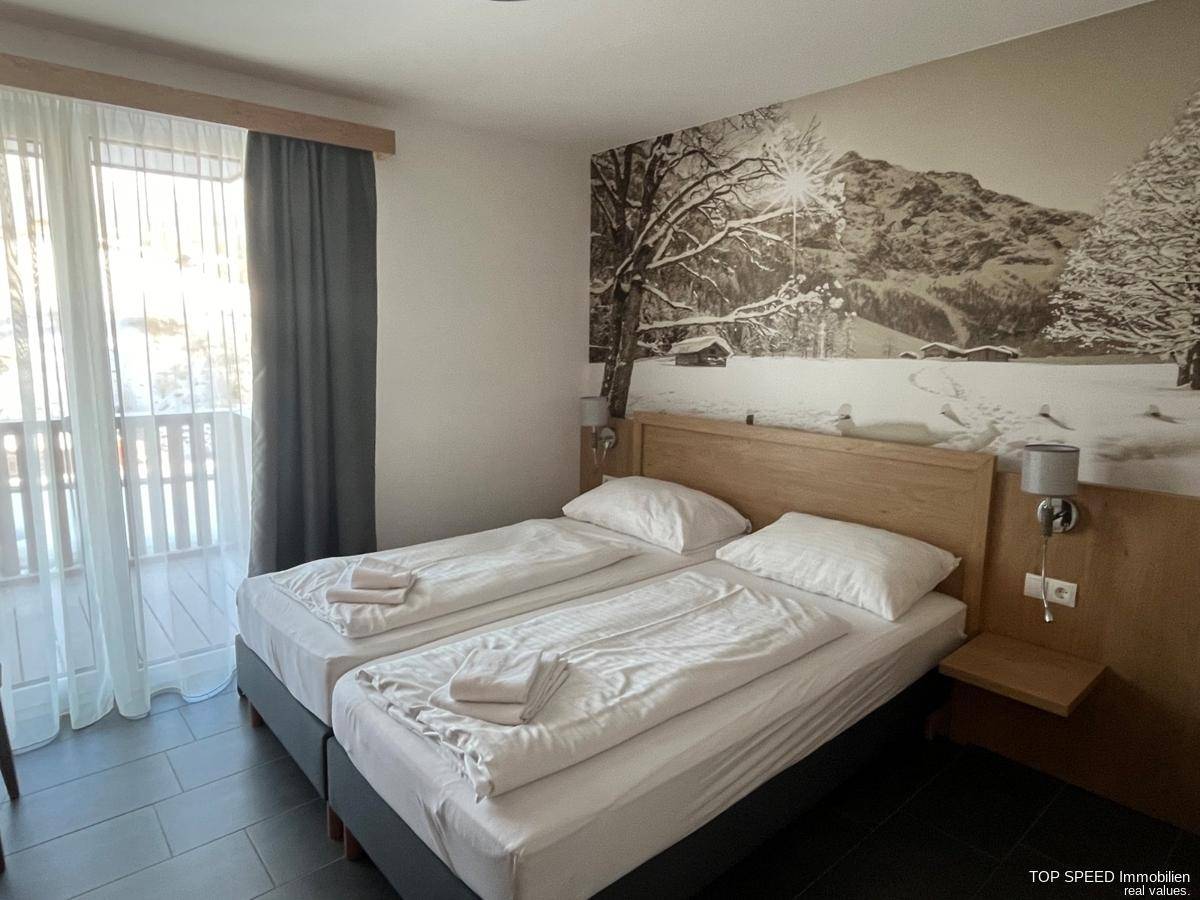 Gemütliches Schlafzimmer mit Doppelbett, Wandtapete mit Wintermotiv und Balkonzugang.