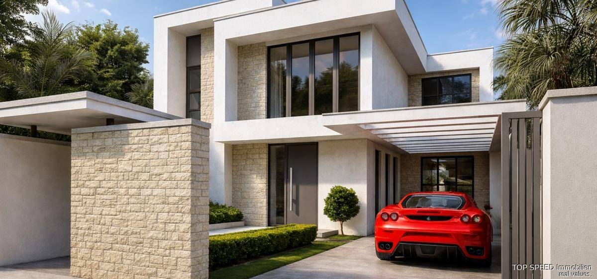Moderne Villa mit eleganter Fassade, Natursteinakzenten und einem roten Sportwagen in der Einfahrt.