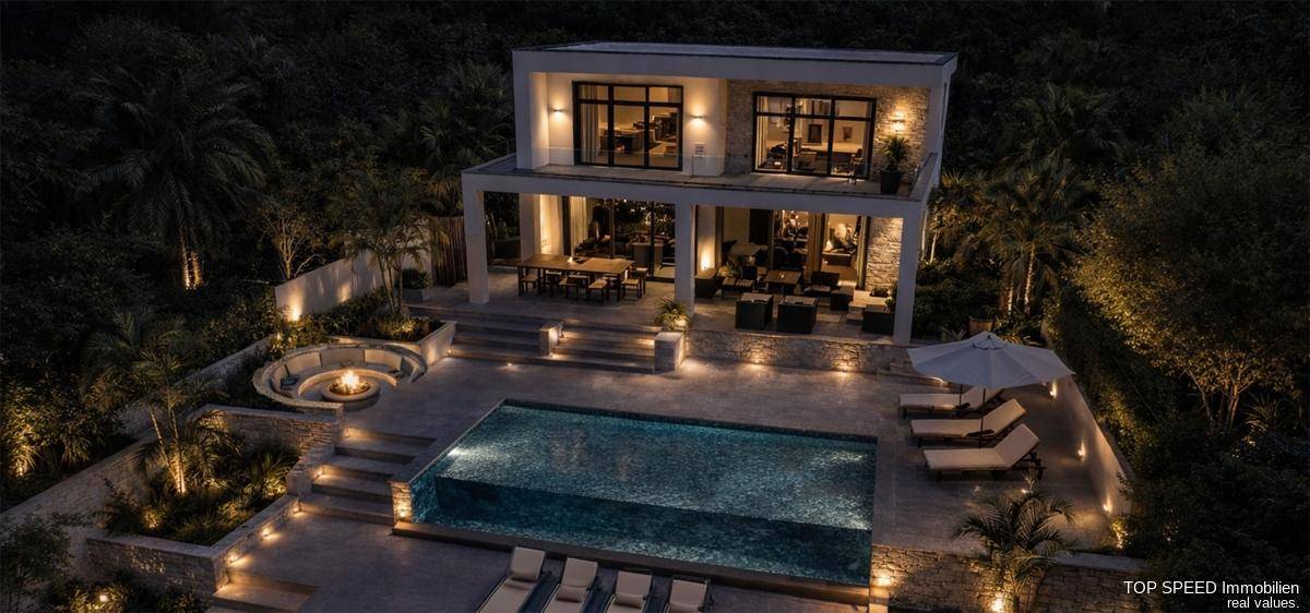 Luxuriöse Villa bei Nacht aus der Vogelperspektive mit beleuchtetem Pool, Feuerstelle und weitläufigen Terrassen.