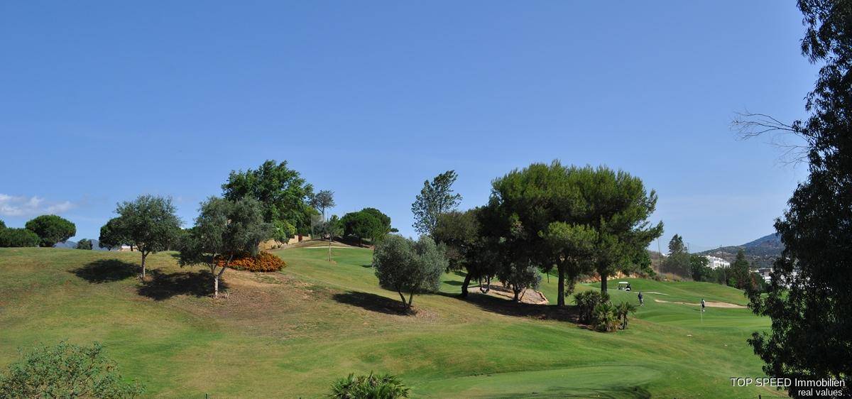Malerische Golfplatzlandschaft mit gepflegten Grüns, Bäumen und einem weiten Horizont.