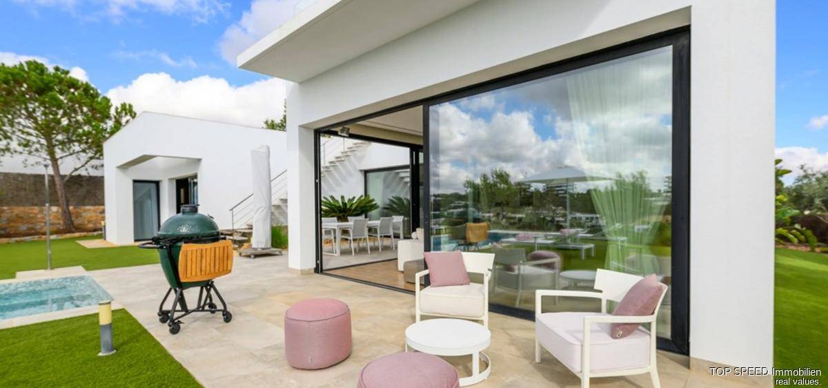 Geräumige Terrasse mit bequemen Sitzgelegenheiten und Blick auf den Garten und Poolbereich.