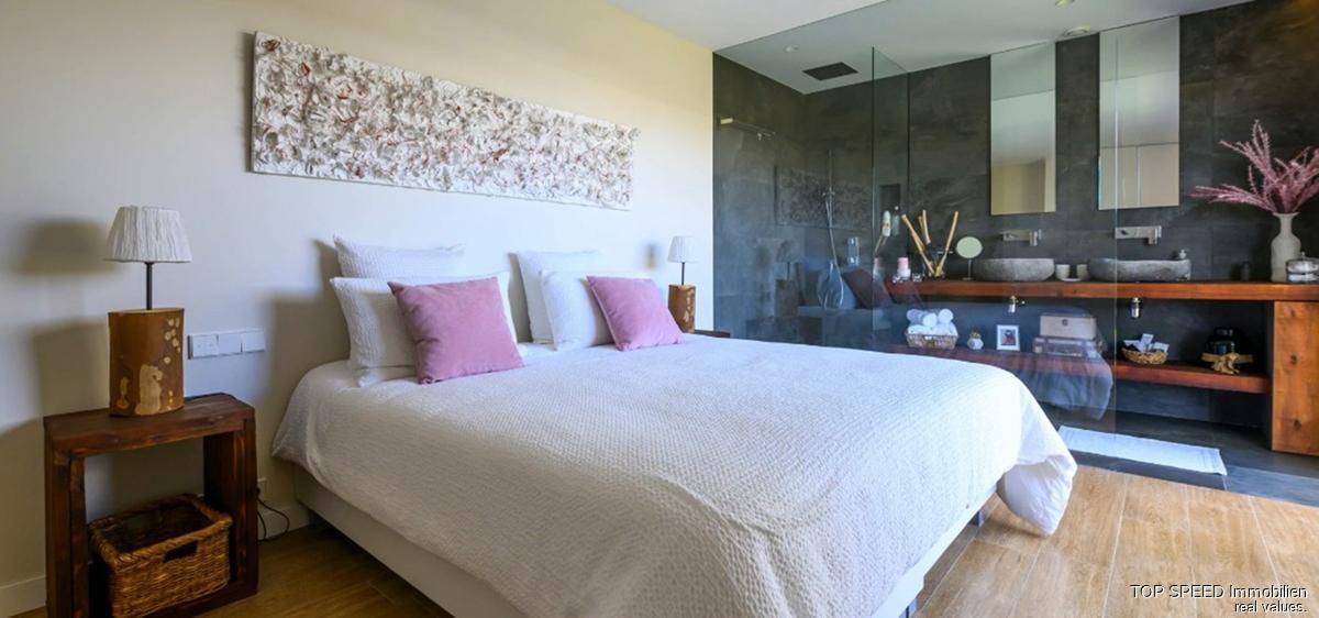 Helles Schlafzimmer mit stilvoller Dekoration und direktem Zugang zum modernen Badezimmer.