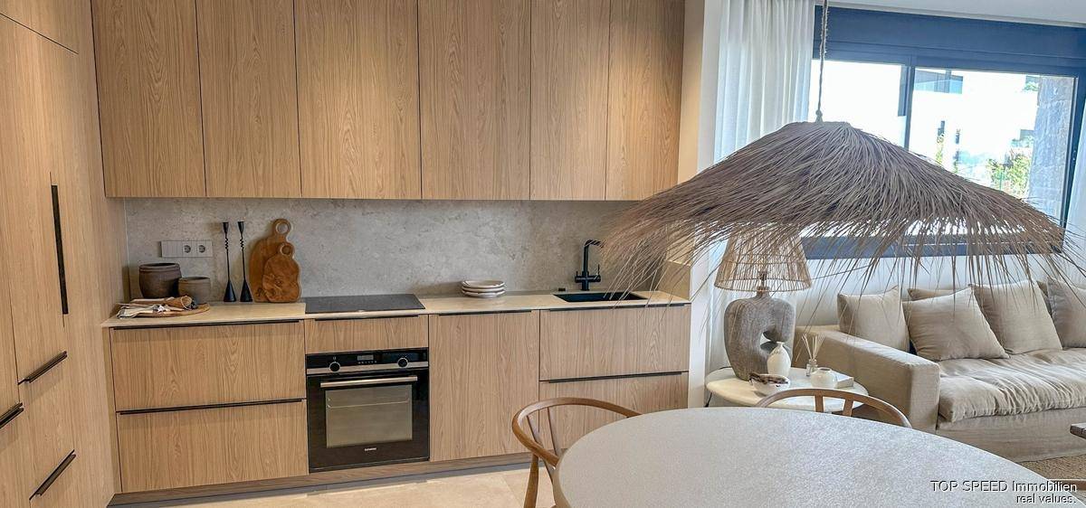 Moderne Holzküche mit integriertem Backofen, Kochfeld und viel Stauraum in den Oberschränken.