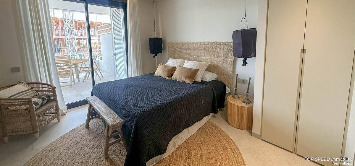 Gemütliches Schlafzimmer mit Doppelbett, Einbauschränken und Zugang zu einem Balkon oder einer Terrasse.