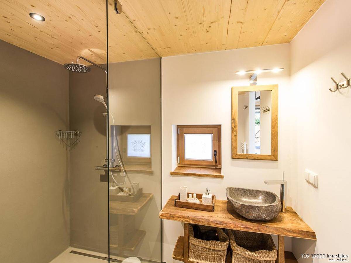 Modernes Badezimmer mit begehbarer Dusche, Steinwaschbecken und Holzdecke.