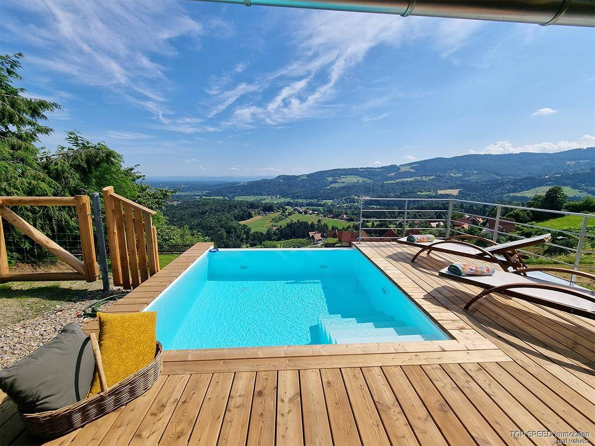 Infinity-Pool auf einer Holzterrasse mit atemberaubendem Blick auf die grüne Landschaft.