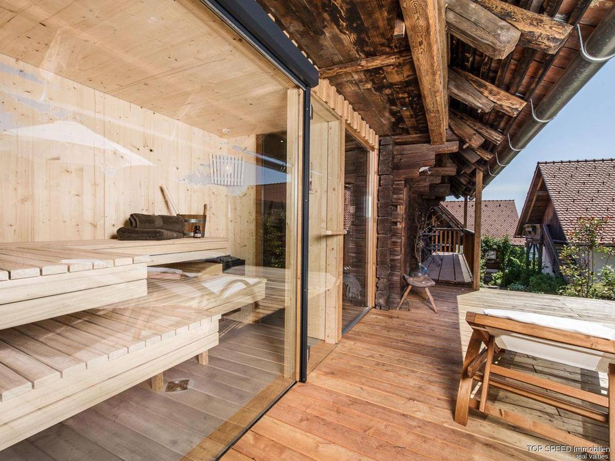 Außenbereich mit Sauna, Holzterrasse und Blick auf die umliegende Landschaft.