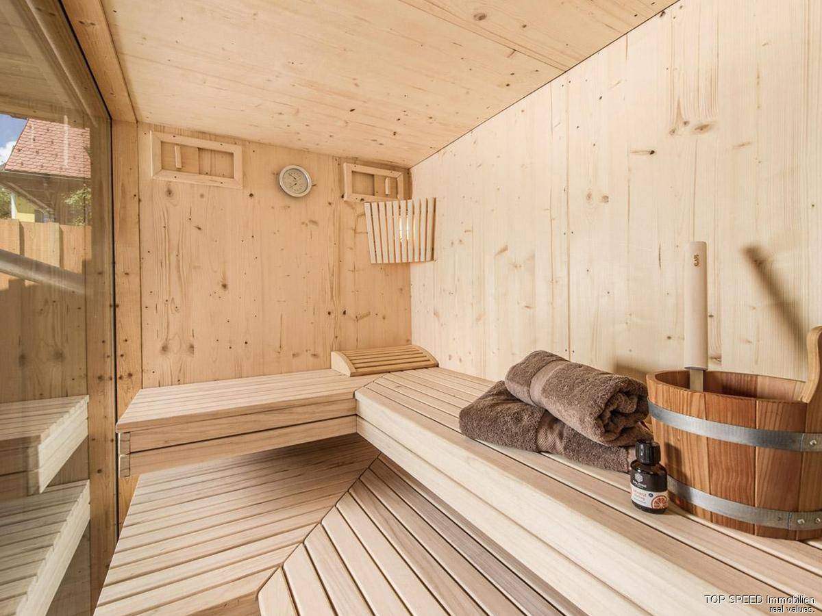 Helle Sauna aus hellem Holz mit traditionellem Eimer und Handtüchern.