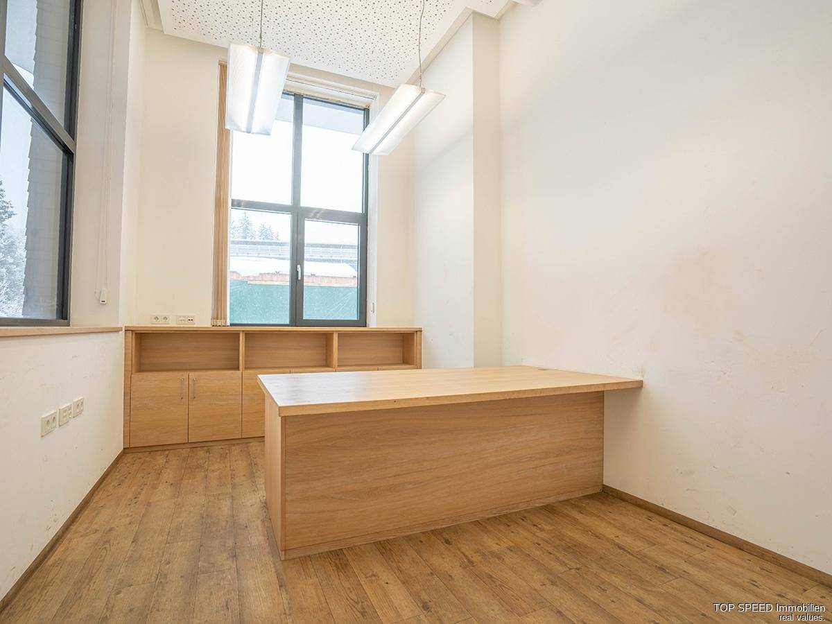 Helles Büro mit Holzboden, großem Schreibtisch und Regalen, bietet eine angenehme Arbeitsatmosphäre.