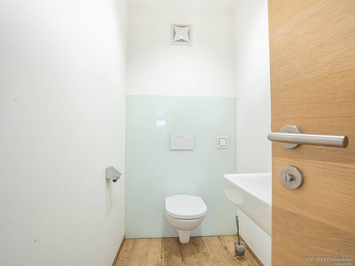 Helles Badezimmer mit Toilette, Waschbecken und Abluftventilator, in sauberem und gepflegtem Zustand.