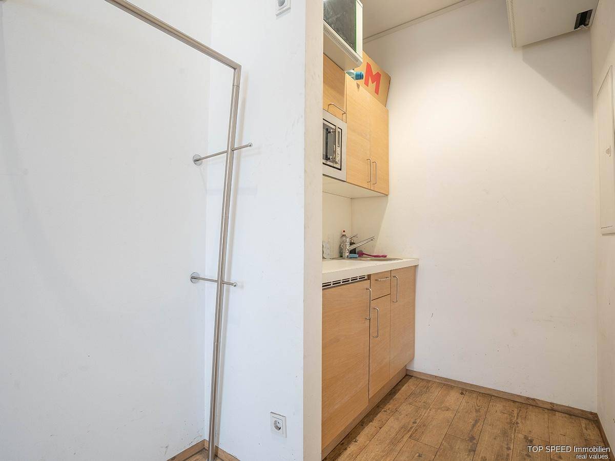 Kleine Küchenzeile mit Holzboden, Spüle und Mikrowelle, praktisch für schnelle Mahlzeiten.