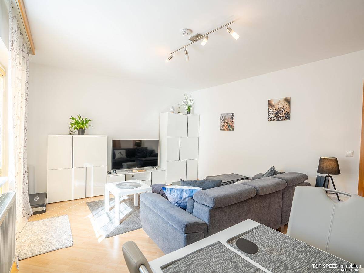 Gemütlicher Wohnbereich mit Fernseher, Sofa und Blick auf den Essbereich.