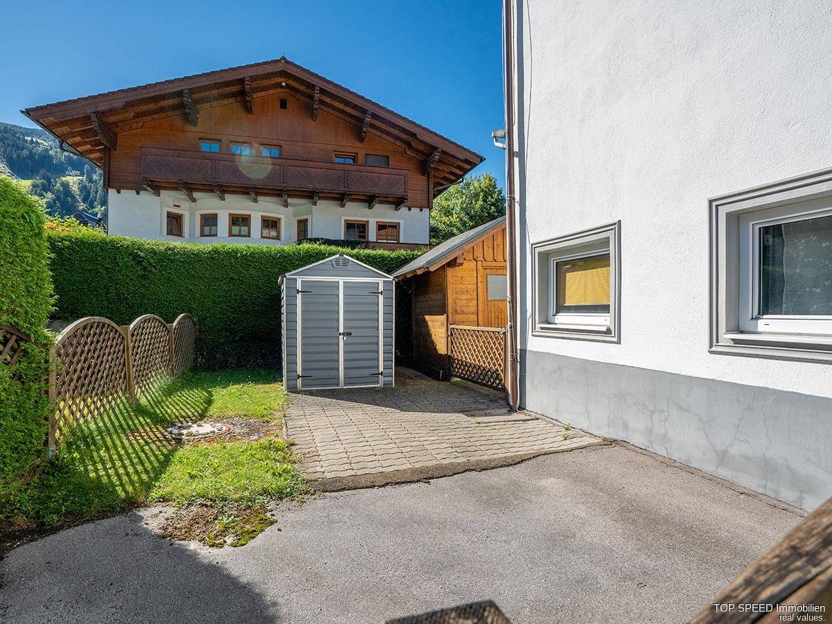 Außenbereich mit Gartenhaus, gepflastertem Weg und Parkmöglichkeit.