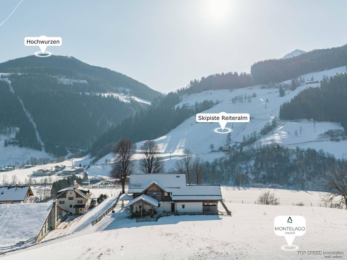 Winterliche Luftaufnahme der Chalets in verschneiter Berglandschaft mit Blick auf Skipisten.