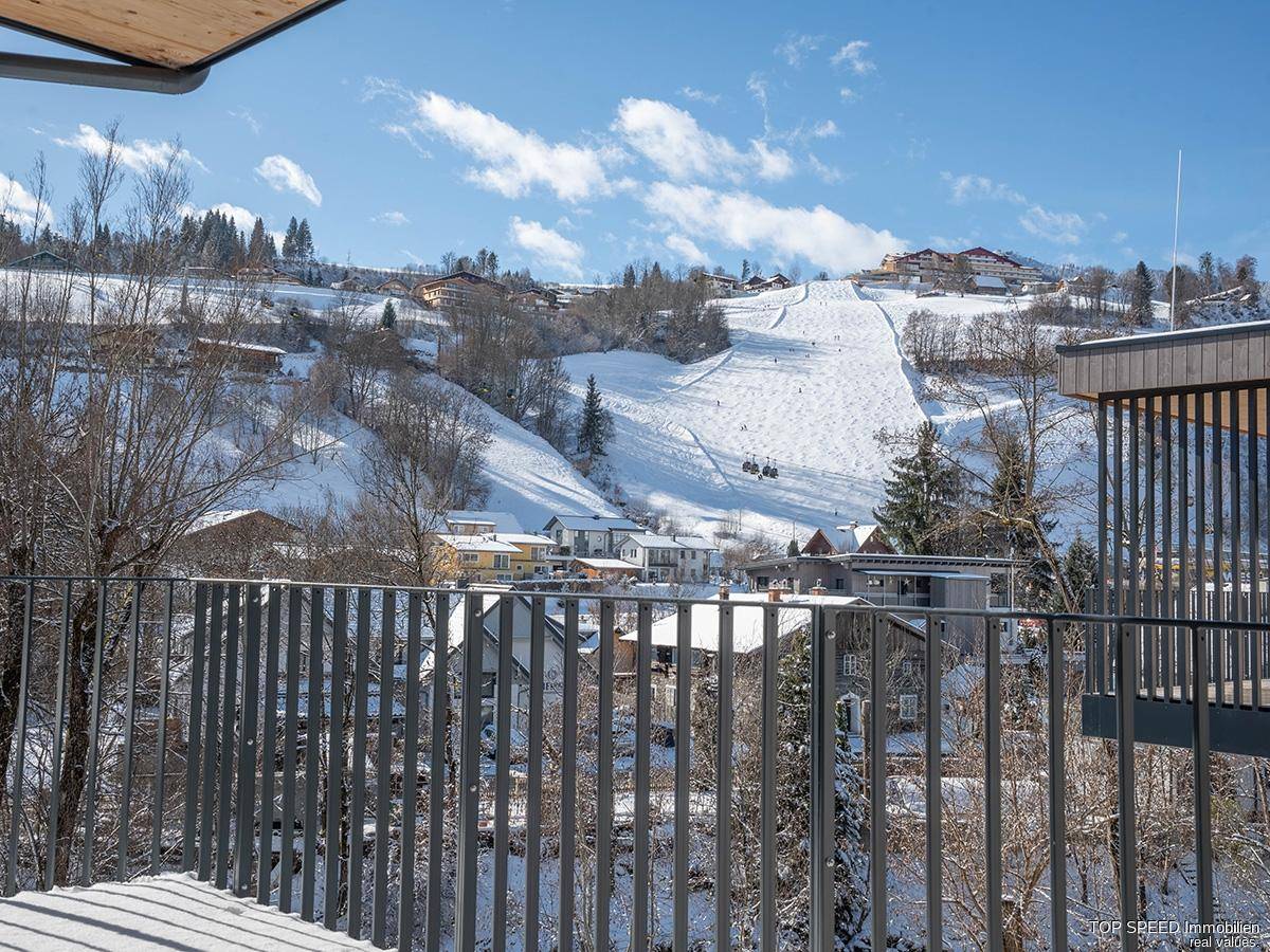 Panoramablick von der schneebedeckten Terrasse auf die Skipiste und die Alpen.