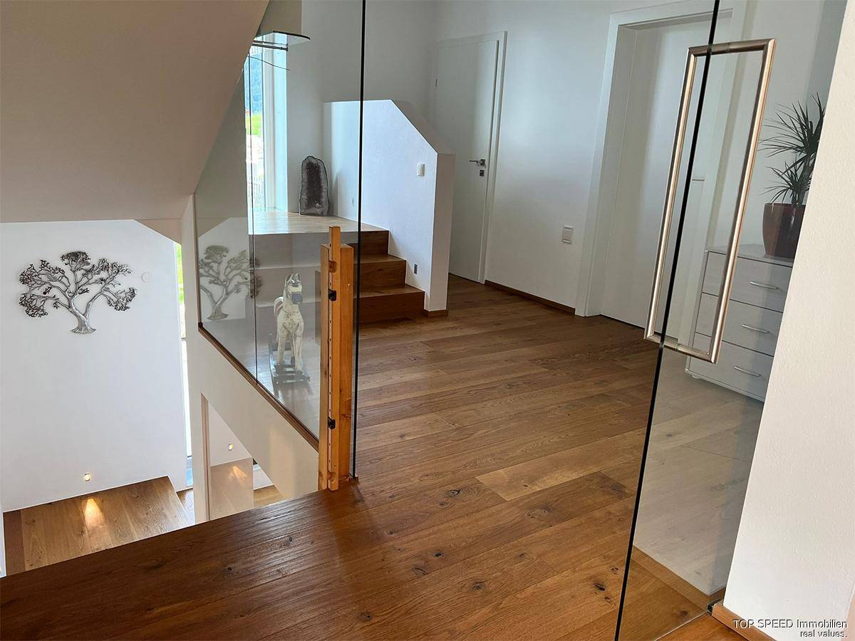 Heller Treppenbereich mit Glasgeländer und hochwertigem Echtholzparkett.
