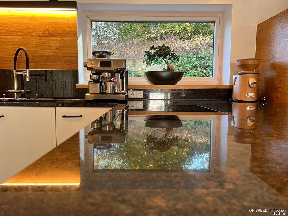 Detailansicht der Küchenarbeitsplatte mit Kaffeemaschine und Fensterblick in die Natur.