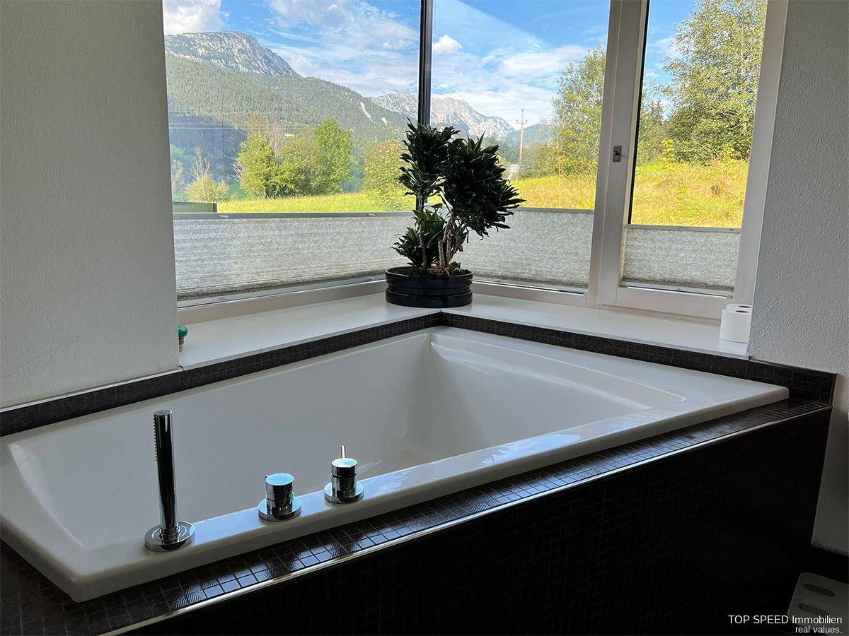 Modernes Badezimmer mit eingelassener Badewanne und Panoramablick auf die Berge.