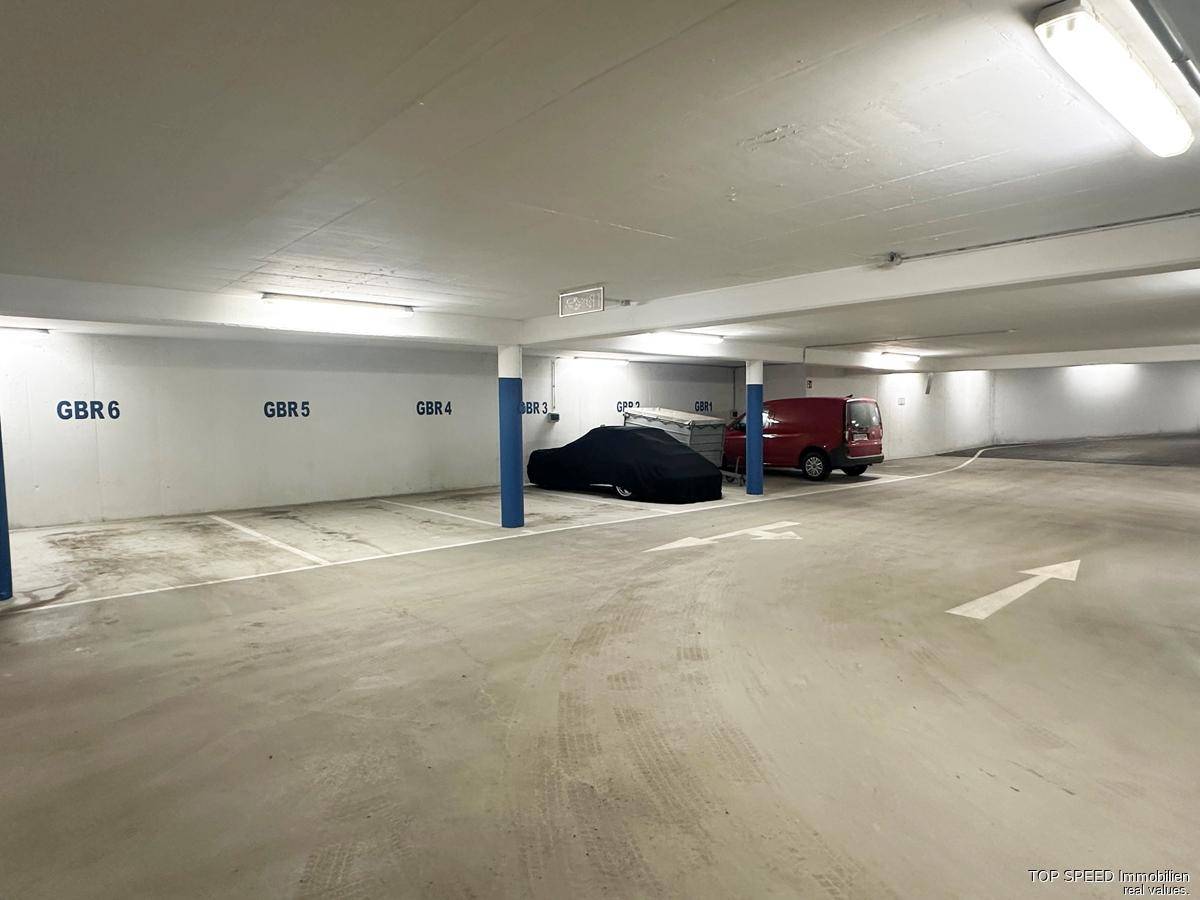 Geräumige und gut beleuchtete Tiefgarage mit markierten Stellplätzen und Betonboden.
