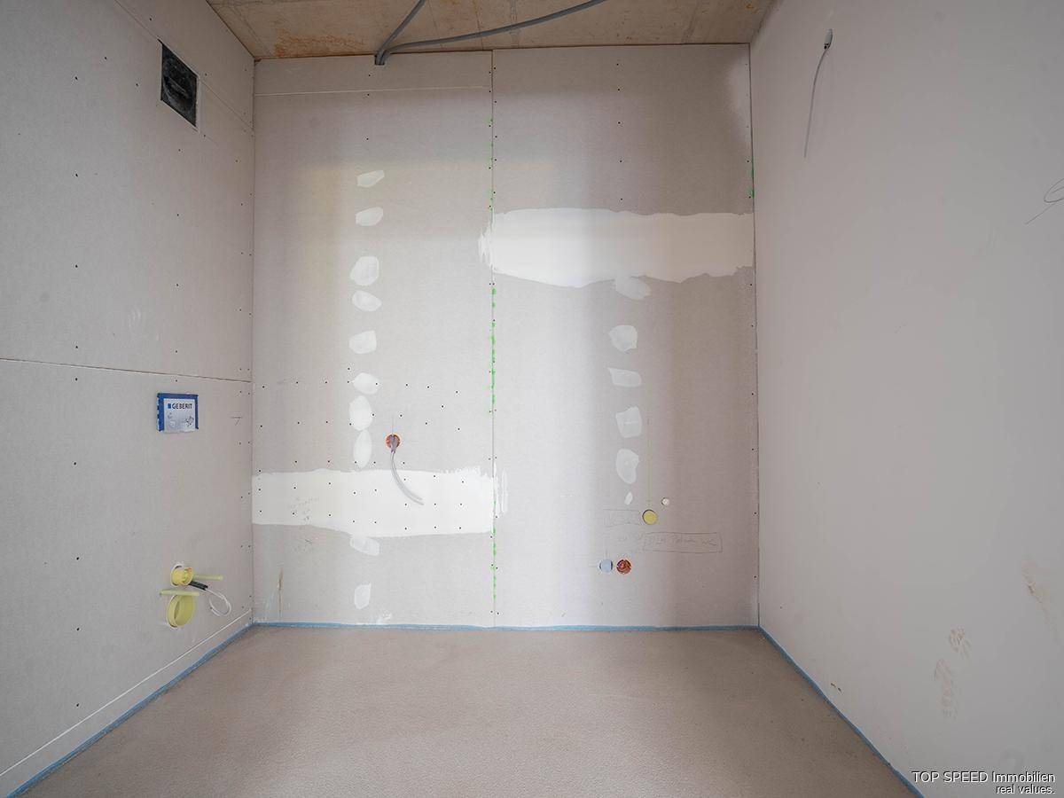 Kleiner Rohbau-Raum mit sichtbaren Wasseranschlüssen und vorbereiteten Wänden für die Endmontage.