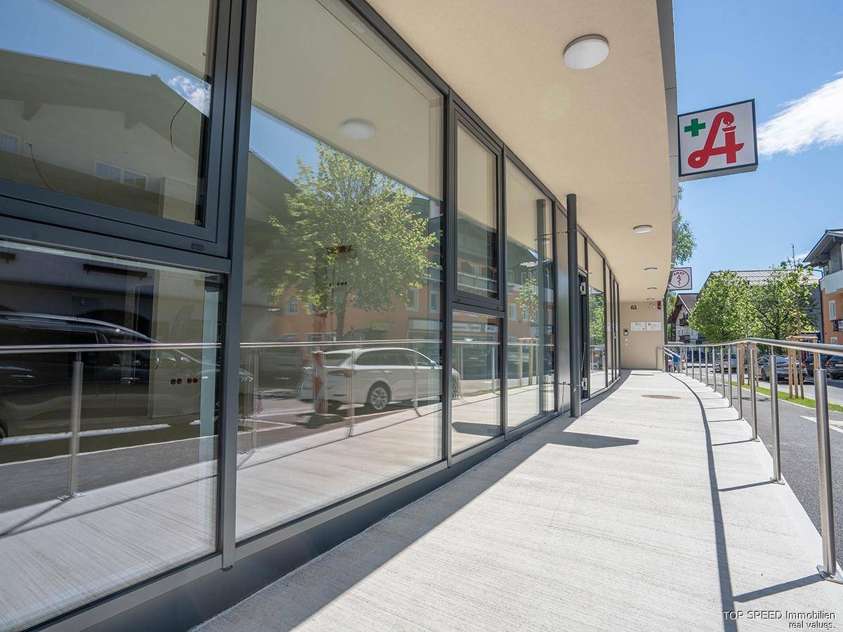 Barrierefreier Zugang zum Gebäude über eine breite Rampe entlang der großen Schaufensterfront.