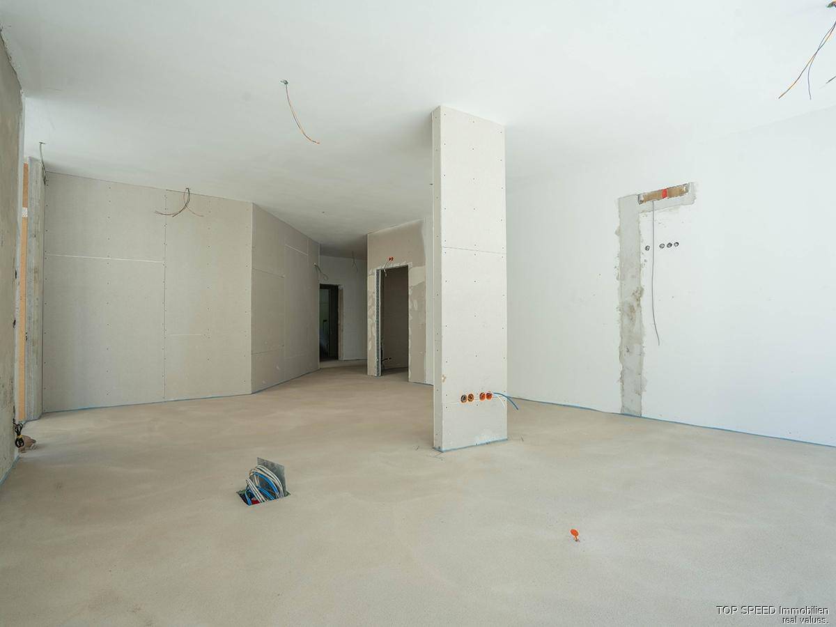 Rohbau eines Innenraums mit Trockenbauwänden und vorbereiteten Anschlüssen für den weiteren Ausbau.