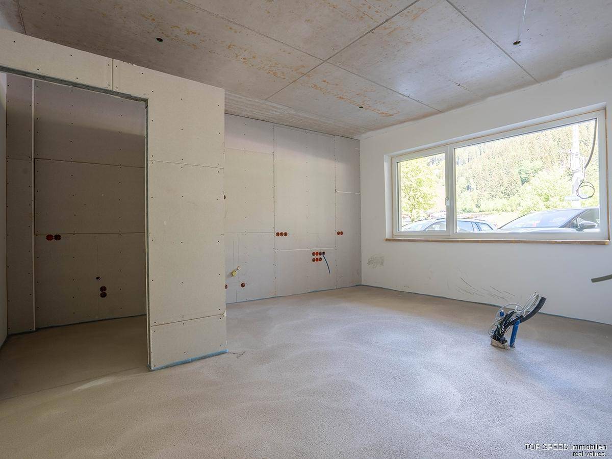 Rohbau-Raum mit Fenster und Blick ins Grüne, ideal für die individuelle Gestaltung.