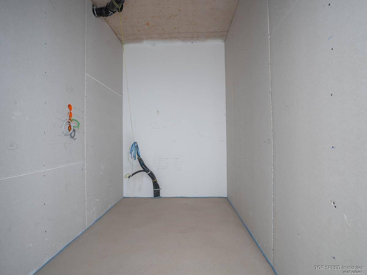 Unfertiger Abstellraum mit Trockenbauwänden und sichtbaren Kabeln für die weitere Installation.