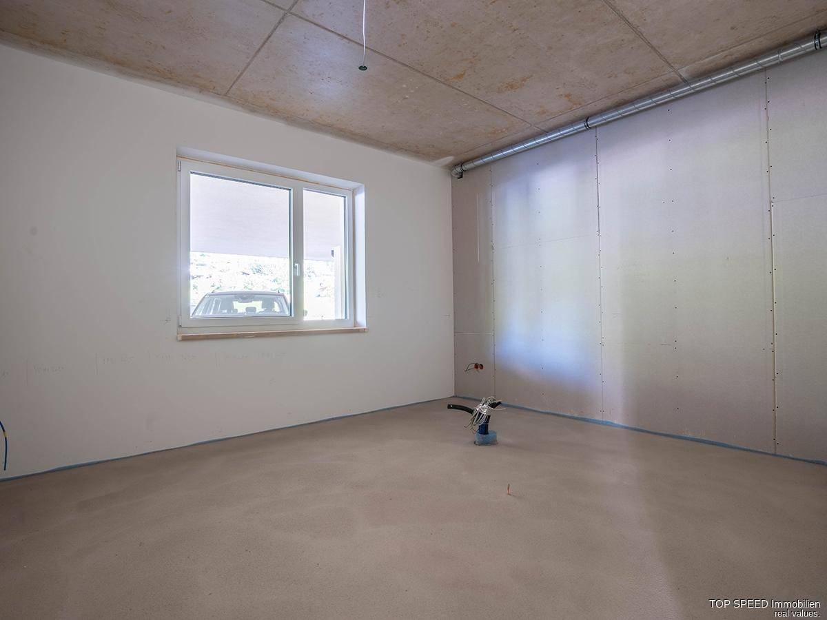 Rohbau-Raum mit Fenster und Blick nach draußen, bereit für den Innenausbau und die Nutzung.