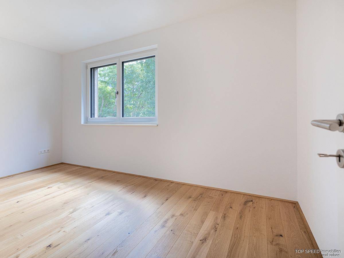 Schlichtes Zimmer mit hellem Parkettboden und einem Fenster, ideal als Schlaf- oder Arbeitszimmer.