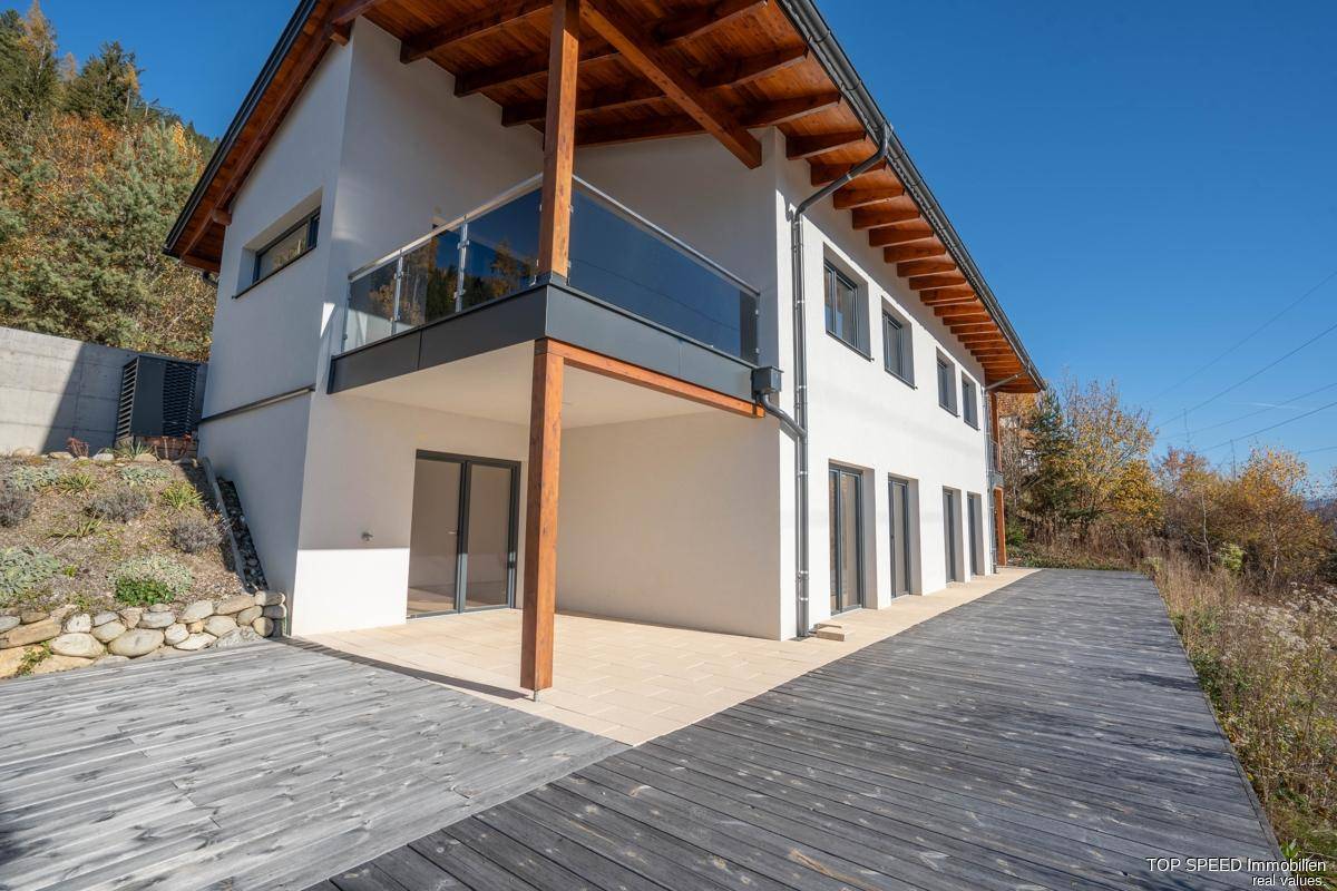 Große Holzterrasse und Balkon an der Seite des modernen Gebäudes mit Blick auf die Umgebung.